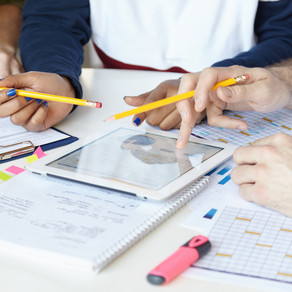 Diagramme_03 Auf einem Tisch liegen Blöcke und Blätter, ein Tablett, welches von einer Hand benutzt wird.